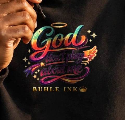 Close-up of the God Don't Play About Me print on the black hoodie, worn.